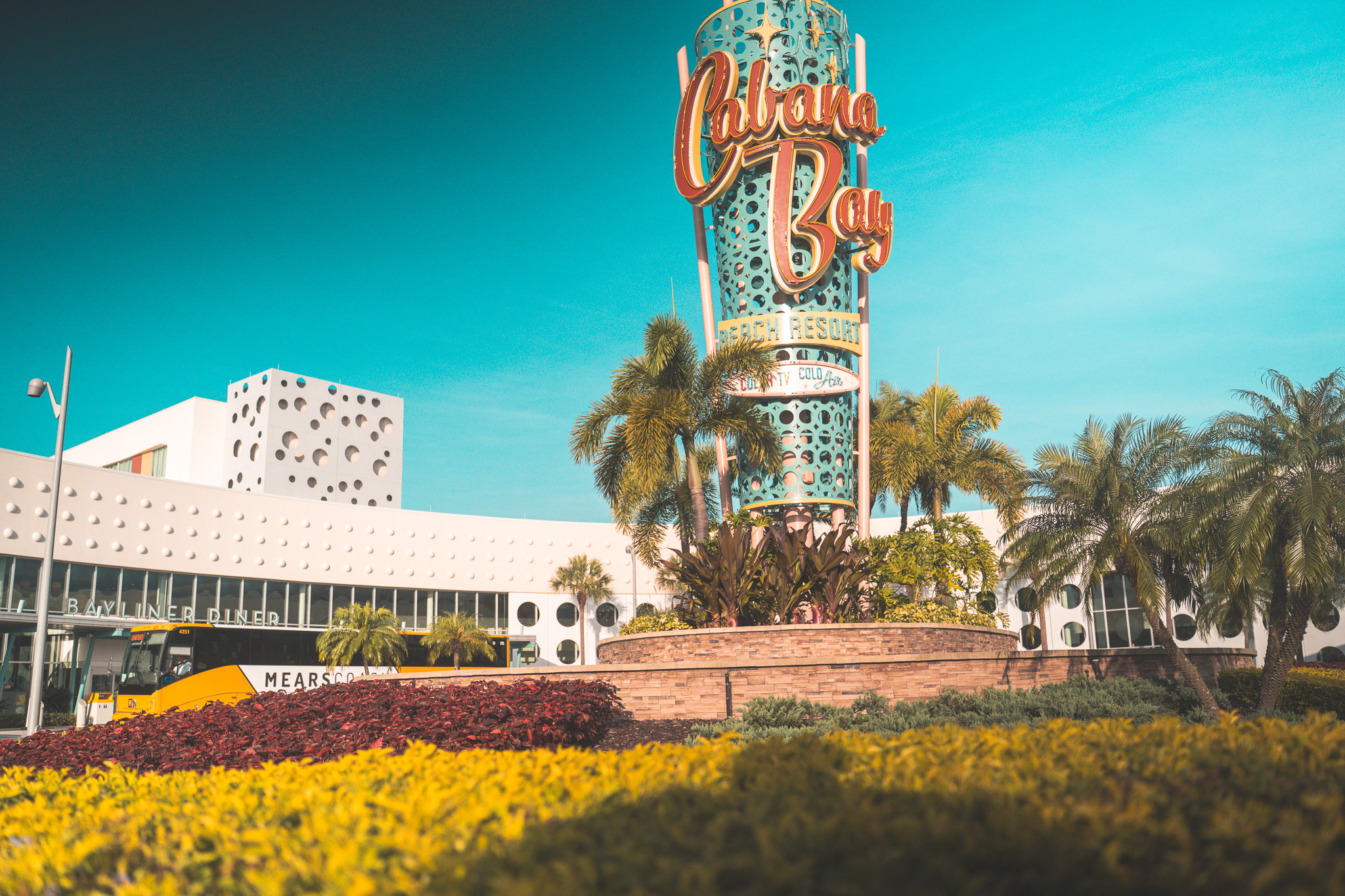 The Cabana Bay Beach Resort sign lit up at Universal Orlando with palm trees and Bayliner Diner in the background