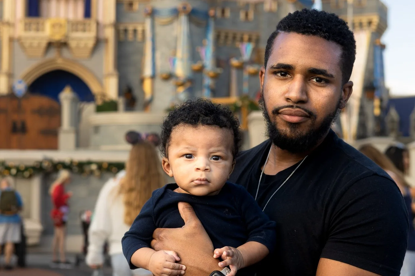 Jordan Roberson holding his newborn baby in front of Cinderella Castle at Magic Kingdom Walt Disney World