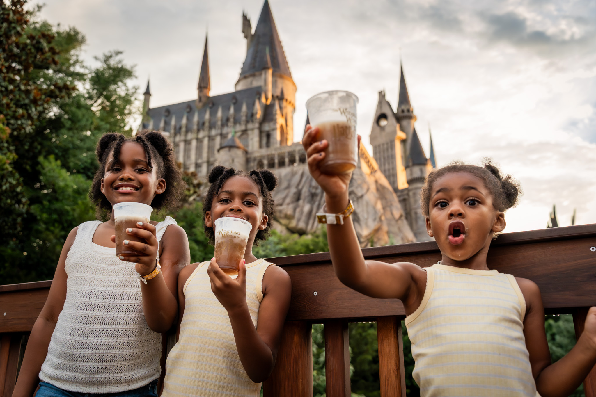 Three Roberson girls holding butterbeers in front of Hogwarts Castle at night during the Orlando Informer Meetup